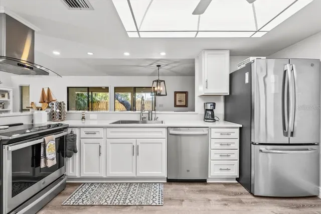 a kitchen with stainless steel appliances granite countertop a refrigerator a stove and a sink