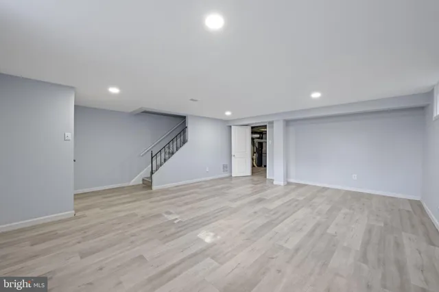 a view of an empty room with wooden floor and stairs