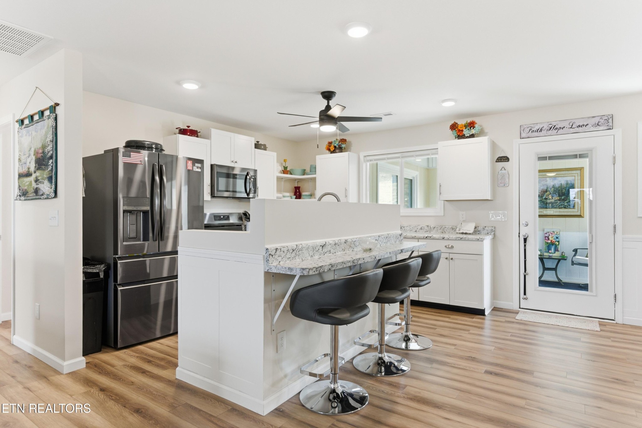 6911 Fairview Road Corryton, TN 37721 - Photo 10 of 30 a kitchen with stainless steel appliances a refrigerator a stove a sink dishwasher a dining table and chairs with wooden floor