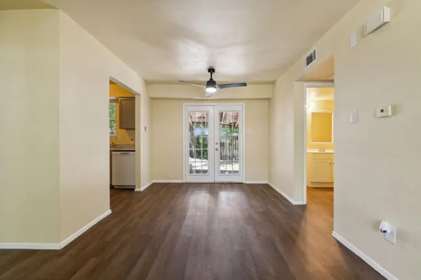 a view of an empty room with wooden floor and a window