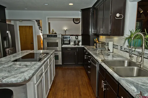 a kitchen with kitchen island granite countertop a sink stove and refrigerator