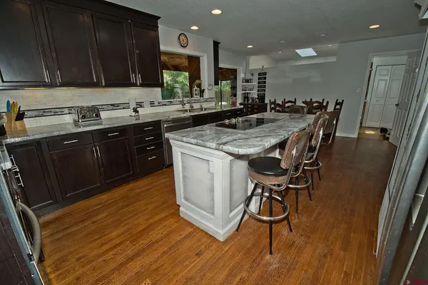 a kitchen with kitchen island granite countertop wooden floors and a sink