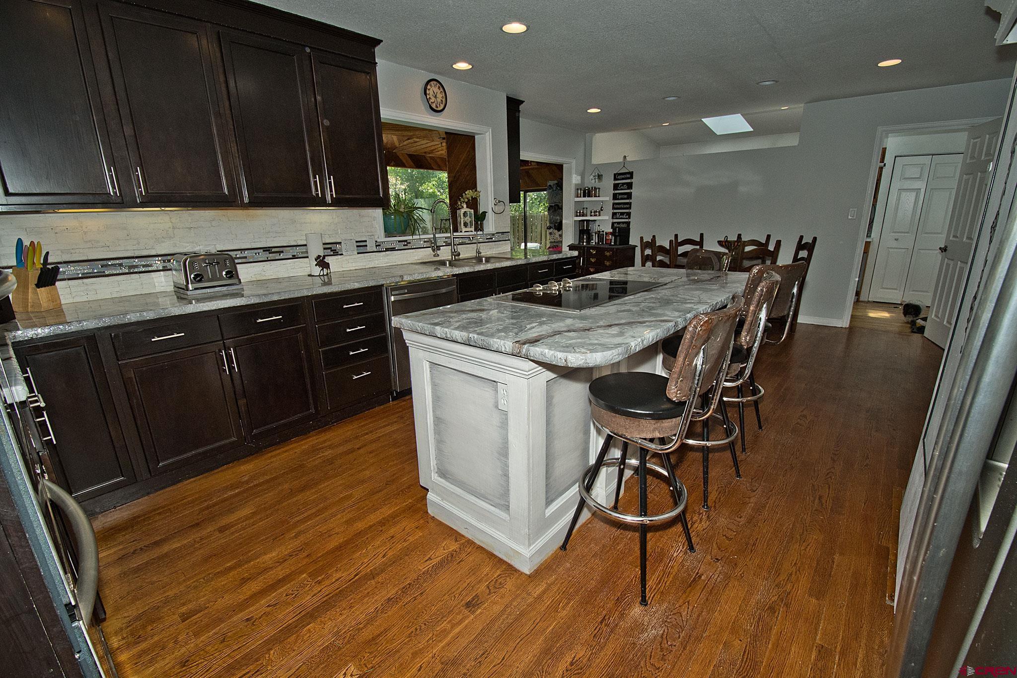 808 Weber Drive Alamosa, CO 81101 - Photo 9 of 44 a kitchen with kitchen island granite countertop wooden floors and a sink