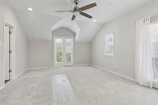 an empty room with chandelier fan and windows