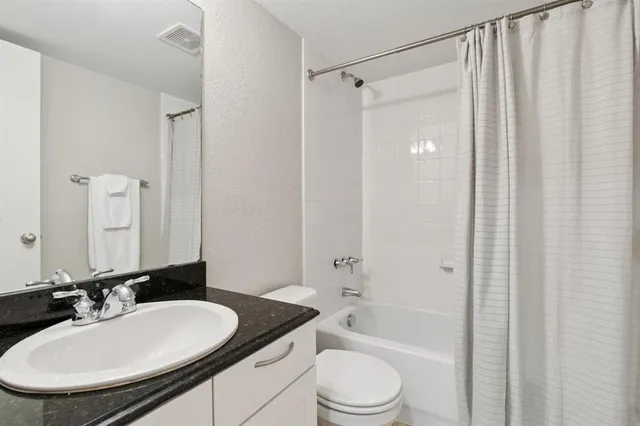 a bathroom with a granite countertop sink toilet a mirror a bathtub and shower