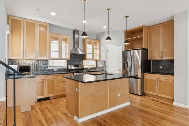 a kitchen with stainless steel appliances granite countertop a refrigerator a sink dishwasher a stove and white countertops with wooden floor