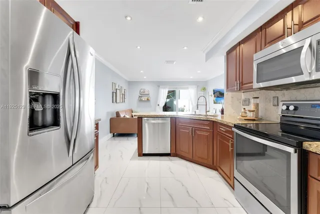 a kitchen with stainless steel appliances granite countertop a refrigerator and a stove top oven