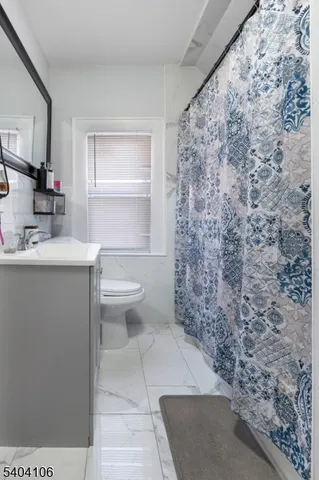 a bathroom with a granite countertop toilet a sink and a mirror