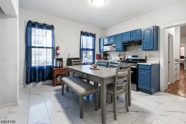 a kitchen with stainless steel appliances a sink a stove a refrigerator cabinets and dining table