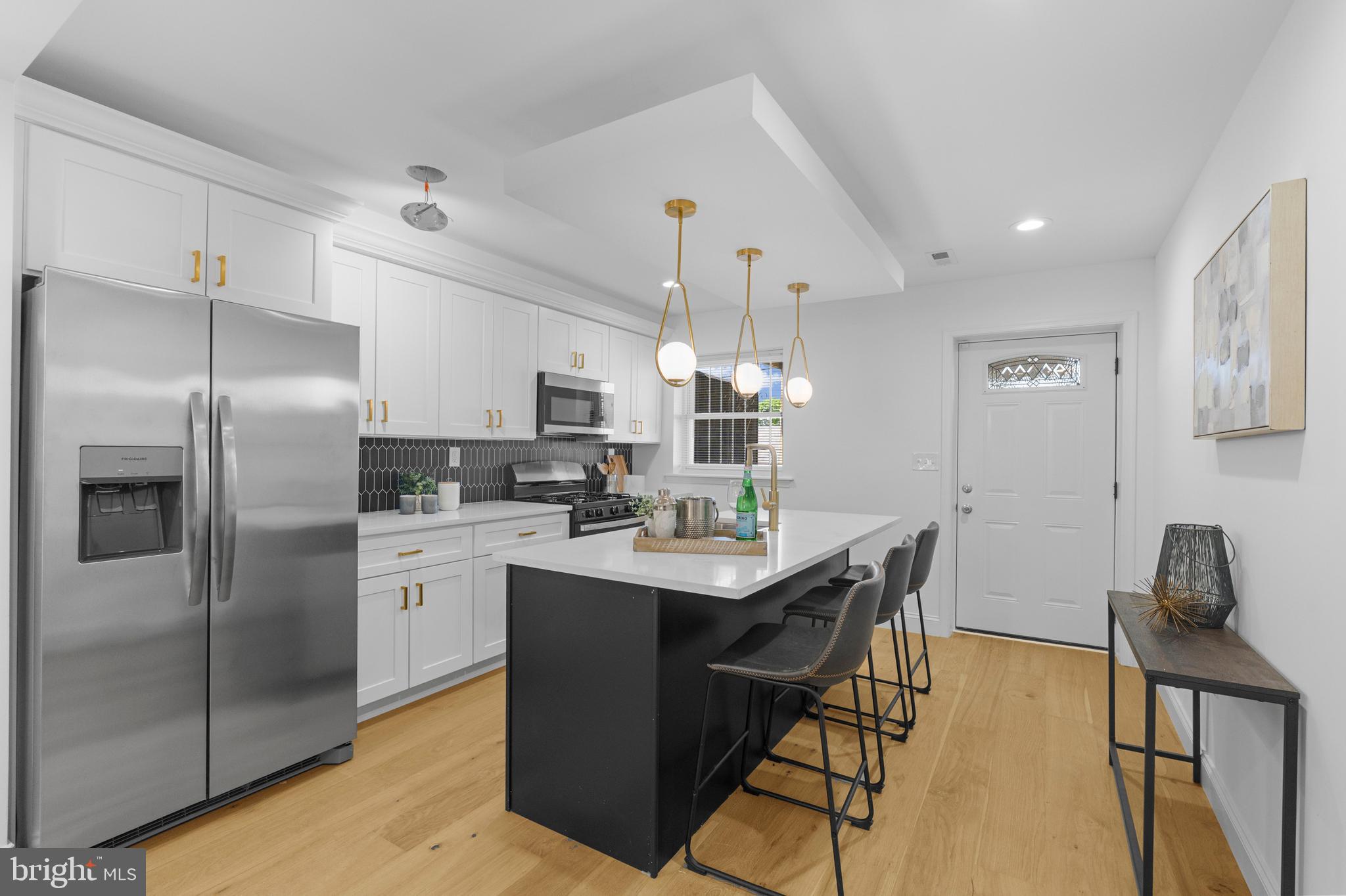 2516 Federal Street Baltimore, MD 21213 - Photo 15 of 40 a kitchen with stainless steel appliances kitchen island granite countertop a table chairs refrigerator and microwave