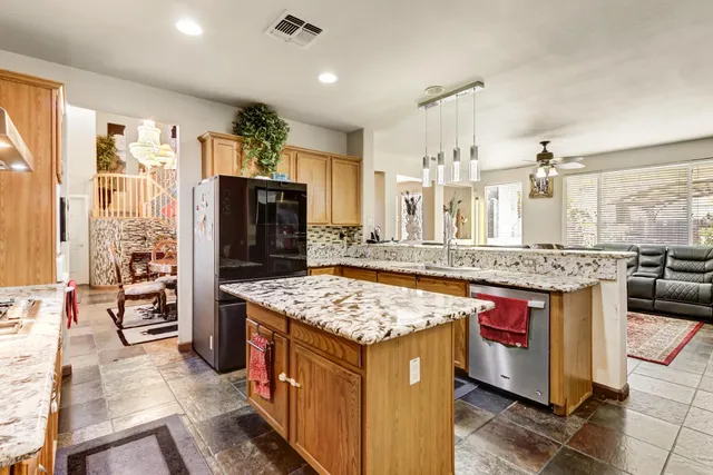 a kitchen with kitchen island granite countertop a sink stove and refrigerator