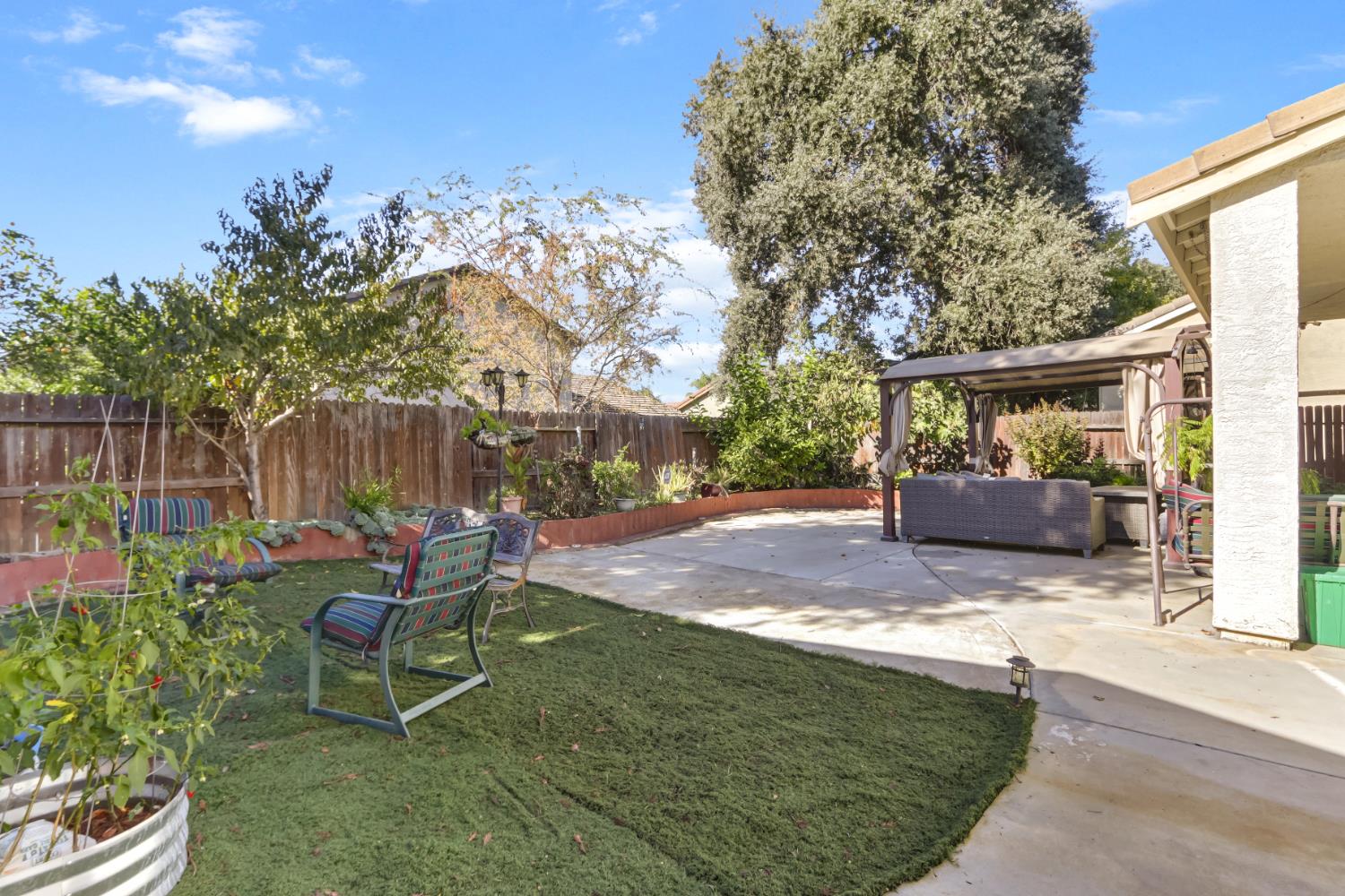 9820 Spring View Way Elk Grove, CA 95757 - Photo 45 of 49 a view of a backyard with chairs potted plants and a large tree