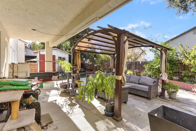 a view of a patio with couches chairs dining table and chairs barbeque grill with a small yard and large trees