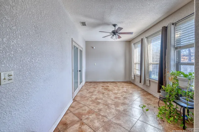 a view of a big room with windows and chandelier fan