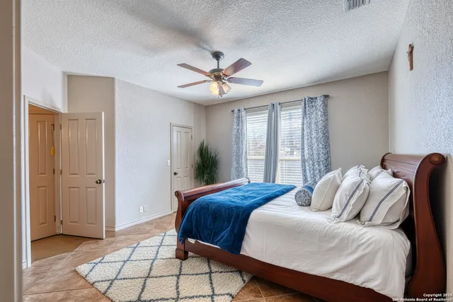 a view of a livingroom with a fireplace a ceiling fan and windows