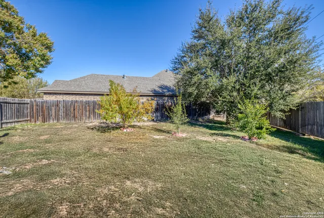 a view of a backyard with a patio and wooden fence