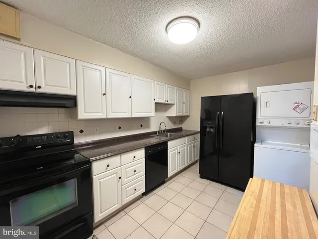 a kitchen with white cabinets and black appliances