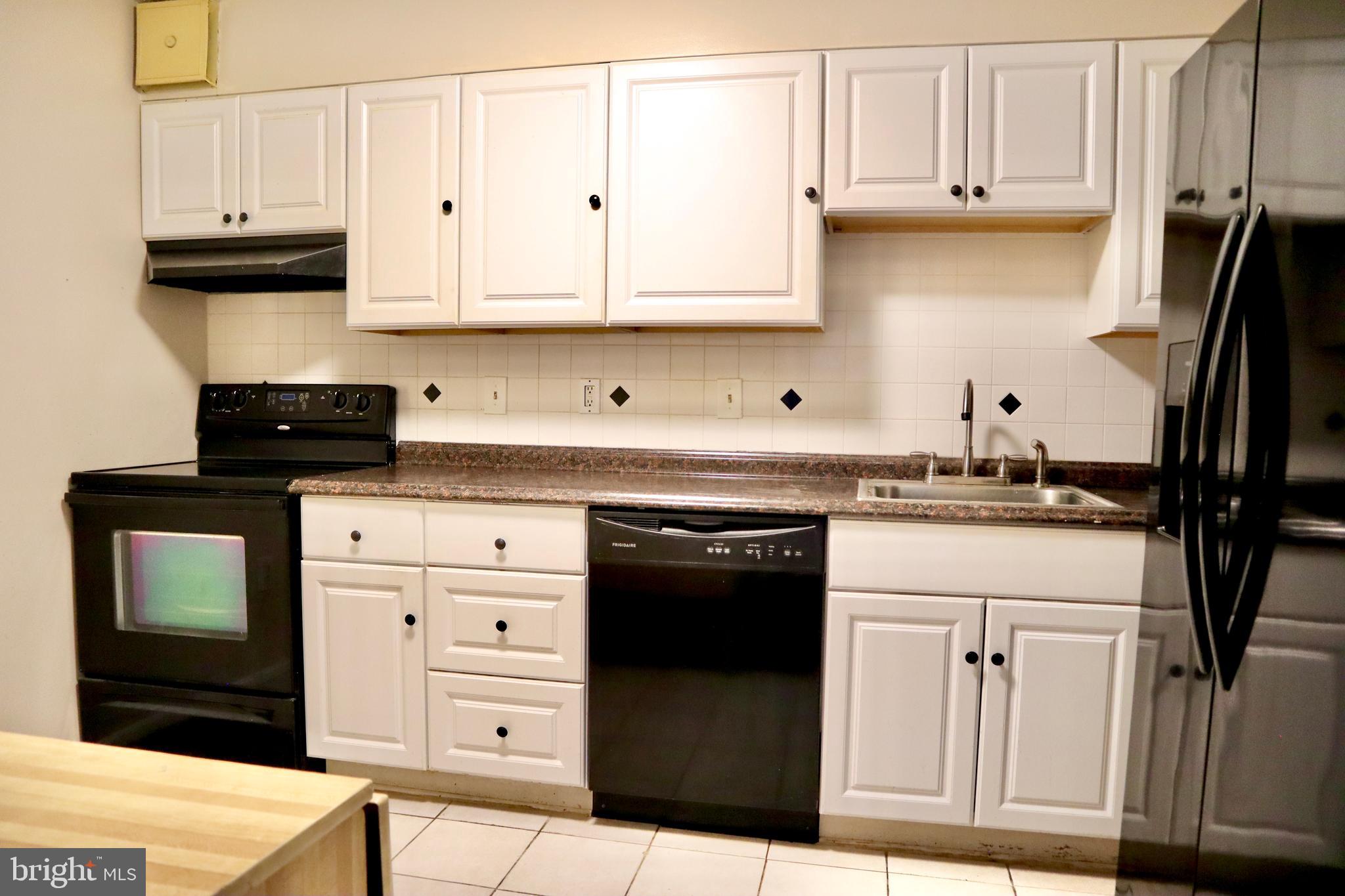 15107 Interlachen Drive, Unit 2119 Silver Spring, MD 20906 - Photo 24 of 53 a kitchen with white cabinets and black appliances