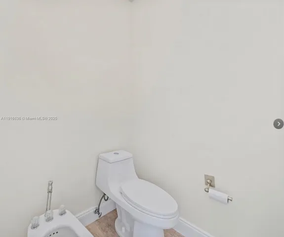 a white toilet sitting next to a white wall