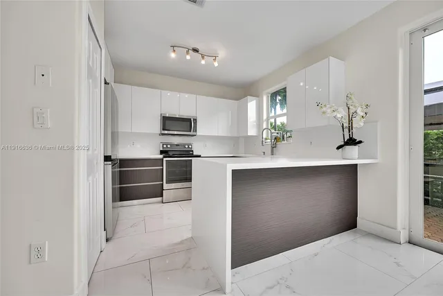 a kitchen with kitchen island white cabinets and stainless steel appliances