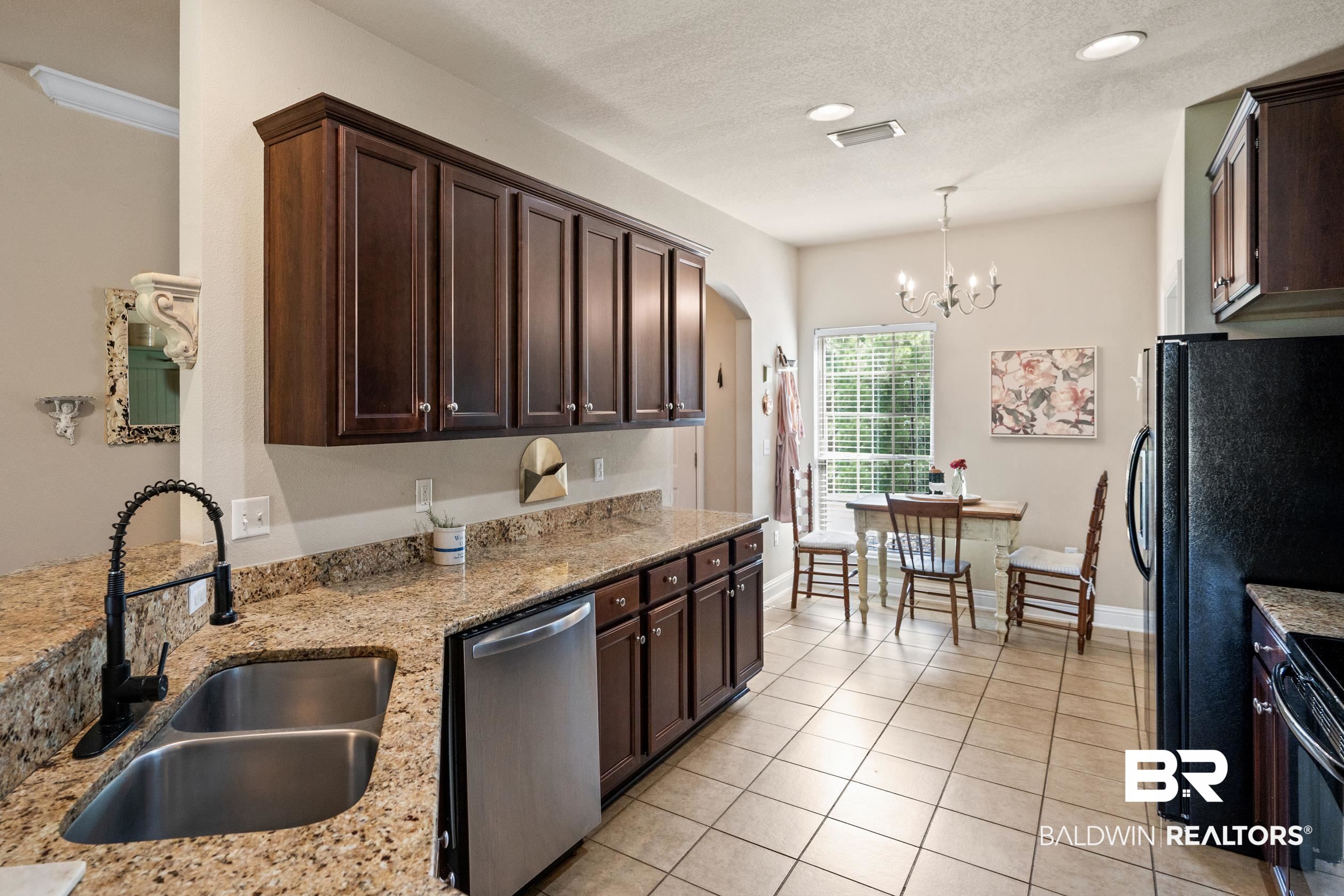 745 Bonaventure Street Fairhope, AL 36532 - Photo 7 of 36 Kitchen featuring light stone countertops, dishwasher, pendant lighting, a notable chandelier, and sink