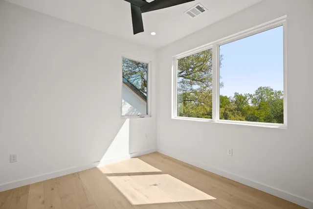 an empty room with a window and a ceiling fan