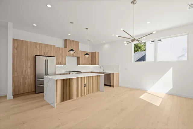 a large kitchen with cabinets a sink and a chandelier