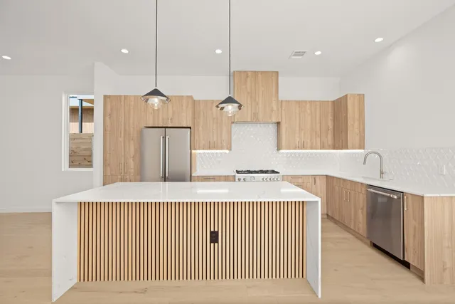 a kitchen with kitchen island granite countertop a stove a sink a refrigerator and white cabinets with wooden floor