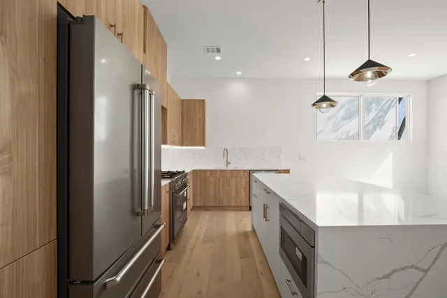 a kitchen with kitchen island granite countertop a refrigerator a sink and wooden floors