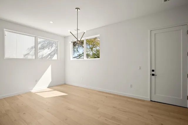 a view of an empty room with window wooden floor and a chandelier