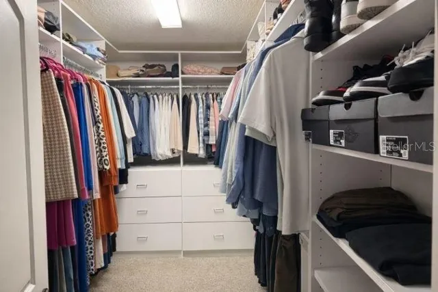 a view of walk in closet with clothes and shoes