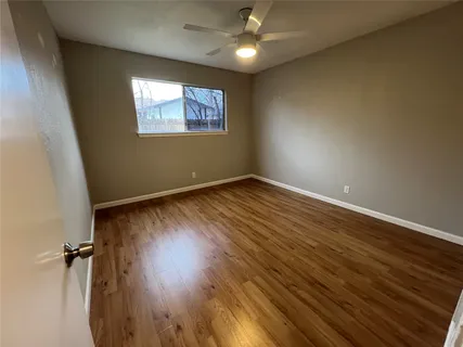an empty room with wooden floor closet and windows