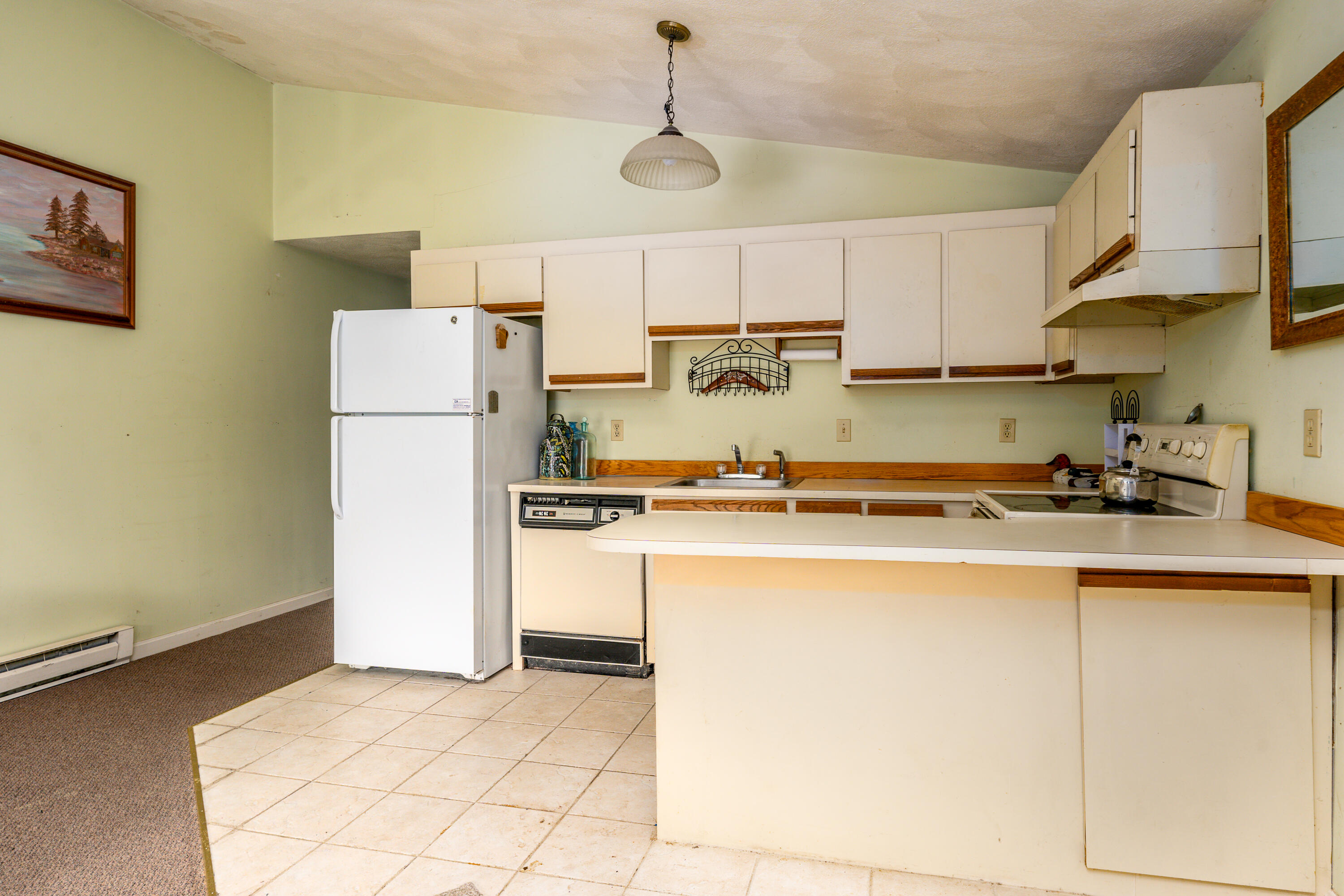 70 Cape Drive, Unit 12D Mashpee, MA 02649 - Photo 6 of 13 a kitchen with a refrigerator a counter top space and cabinets