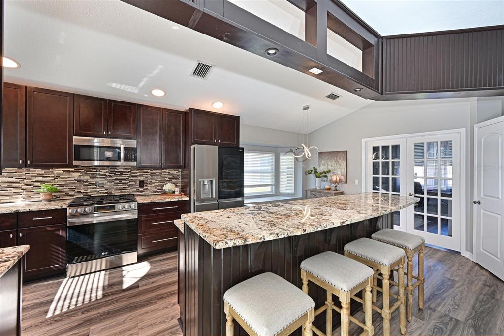 12709 Nightshade Place Lakewood Ranch, FL 34202 - Photo 8 of 53 a kitchen with stainless steel appliances granite countertop a table chairs sink and cabinets