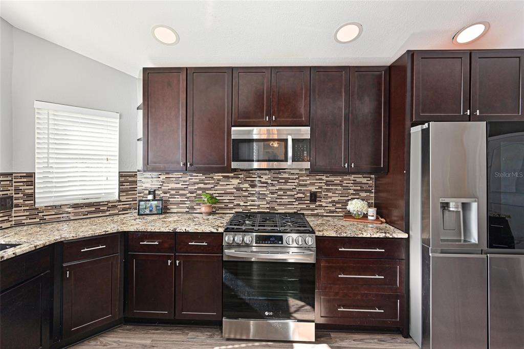 12709 Nightshade Place Lakewood Ranch, FL 34202 - Photo 9 of 53 a kitchen with stainless steel appliances wooden cabinets and a sink
