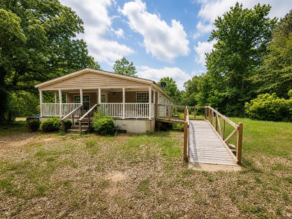 148 Par Road 234 Simsboro, LA 71275 - Photo 1 of 1 Single-story residence featuring light-colored siding, a covered front porch with white railings, and a wooden accessibility ramp with handrails