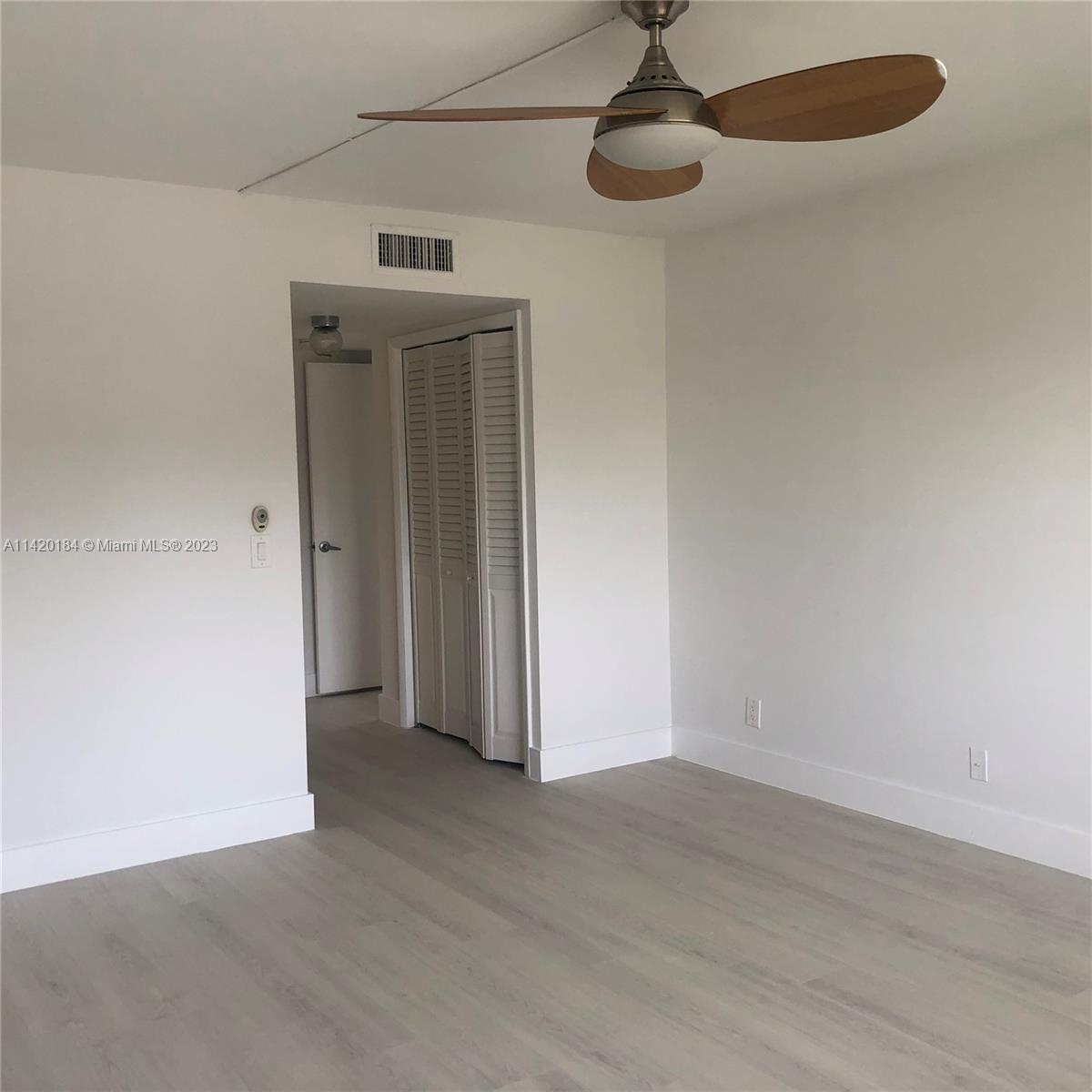 330 Racquet Club Road, Unit 201 Weston, FL 33326 - Photo 25 of 43 an empty room with wooden floor chandelier fan and windows