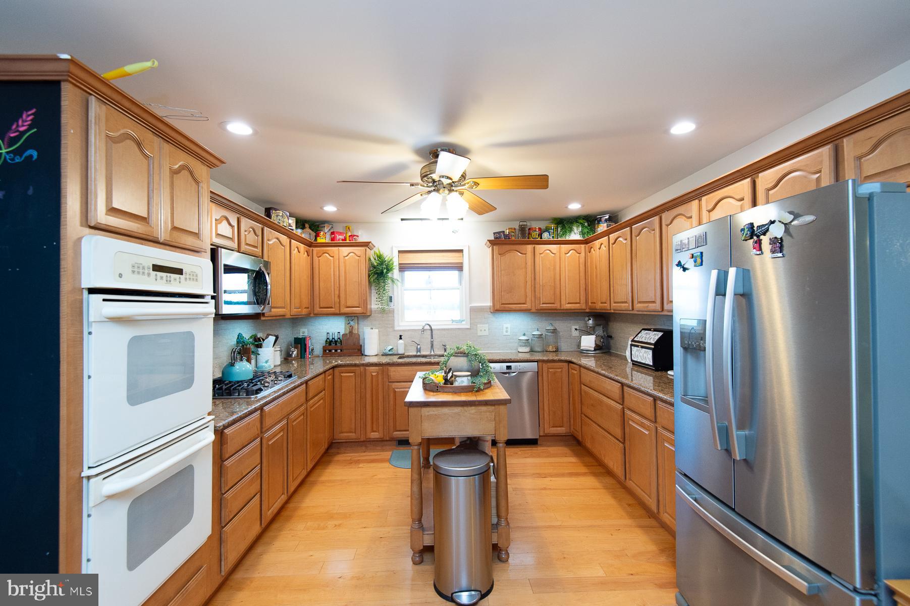 12136 Holly Road Ridgely, MD 21660 - Photo 19 of 136 a kitchen with stainless steel appliances granite countertop a refrigerator a sink dishwasher a stove and white cabinets with wooden floor