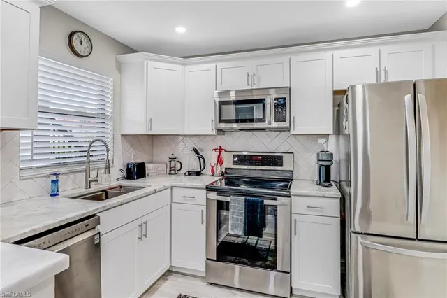 a kitchen with cabinets stainless steel appliances and a window