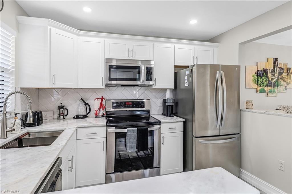 4166 27th Court Southwest, Unit 104 Naples, FL 34116 - Photo 13 of 25 a kitchen with cabinets stainless steel appliances and a sink