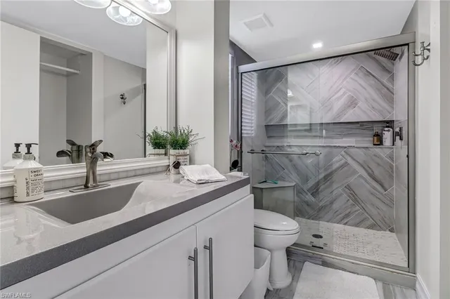 a bathroom with a granite countertop sink toilet and shower