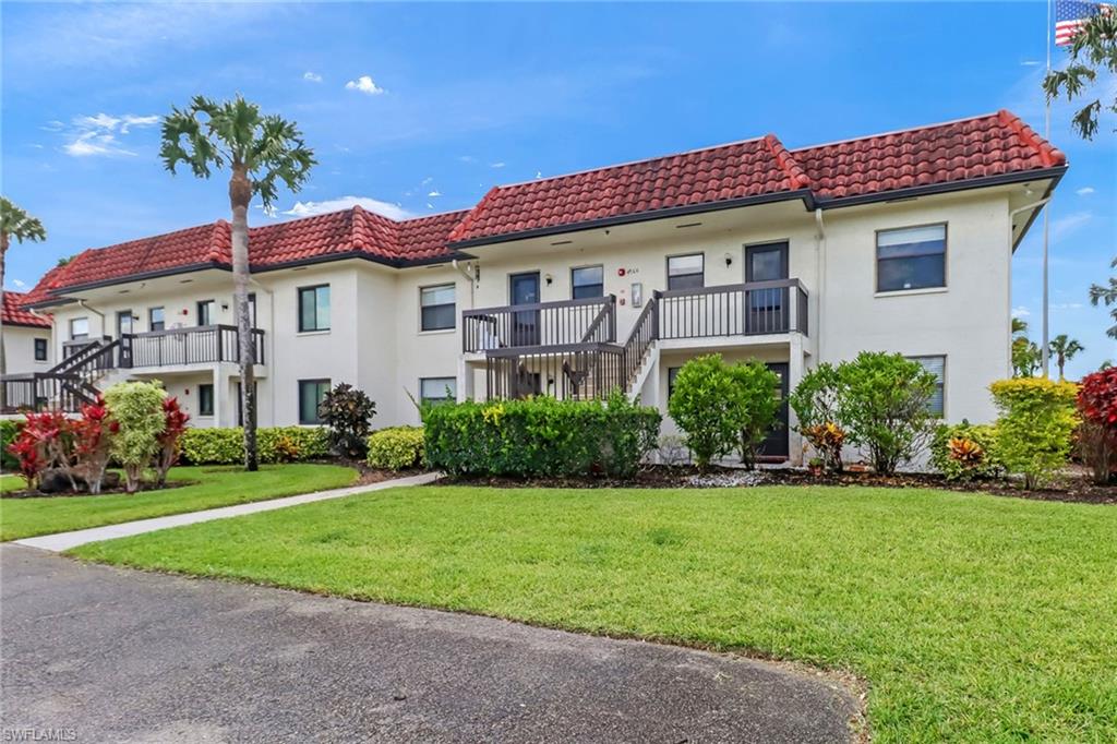 4166 27th Court Southwest, Unit 104 Naples, FL 34116 - Photo 2 of 25 a front view of a house with a yard