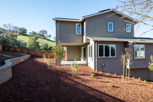 a front view of a house with large trees