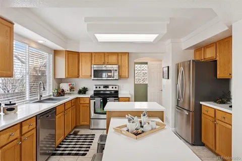 a kitchen with a sink a stove a refrigerator cabinets and a dining table