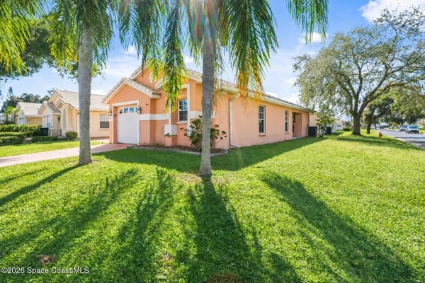 a view of a white house with a big yard and palm trees
