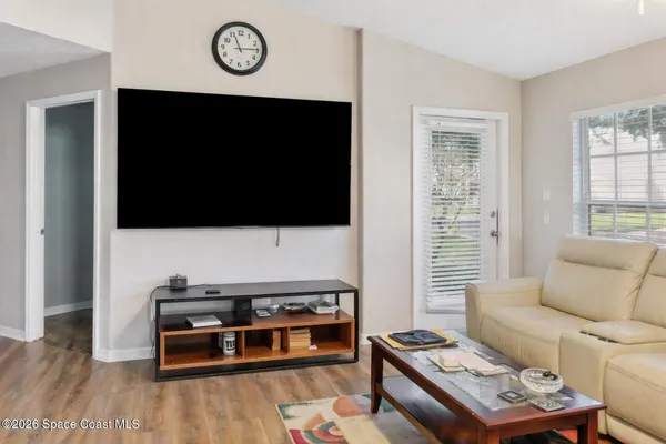 a living room with furniture a flat screen tv and a window