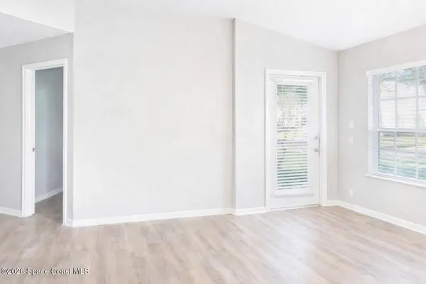 an empty room with wooden floor and windows