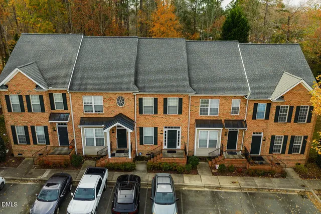 a front view of residential houses with yard and trees