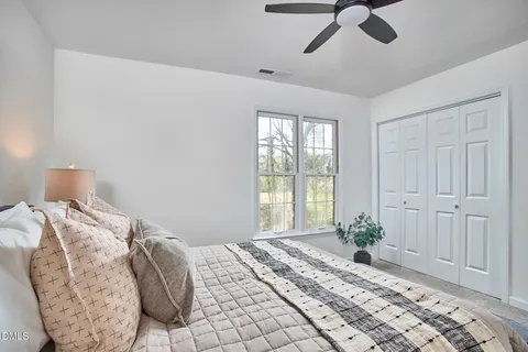 a bed sitting in a bedroom next to a window and a chandelier