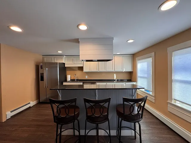 a kitchen with stainless steel appliances a dining table chairs and wooden floor